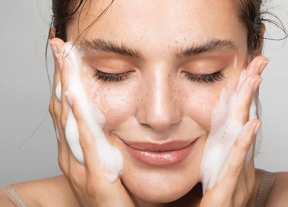 Close up studio shot of a beautiful woman with perfect skin, while she cleaning her face